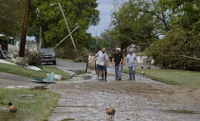 People walk along River St. flood damage is seen Saturday, Sept. 28, 2024, in Newport, Tenn. (AP Photo/George Walker IV)