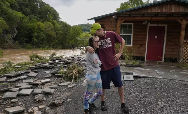 Jonah Wark, right, kisses his wife Sara Martin outside their flood-damaged home on the Pigeon River in the aftermath of Hurricane Helene, Saturday, Sept. 28, 2024, in Newport, Tenn. (AP Photo/George Walker IV)