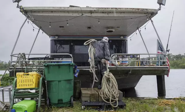 Jason Bledsoe hauls rope to a houseboat in preparation of moving it to a safer dock, Wednesday, Sept. 11, 2024, in Bayou Gauche, La., ahead of Hurricane Francine. (David Grunfeld/The Times-Picayune/The New Orleans Advocate via AP)