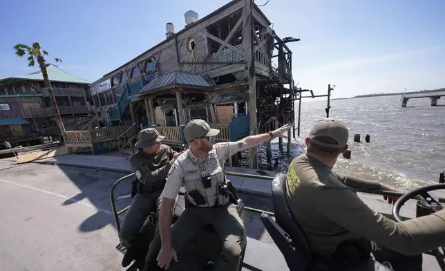 Officer Nate Martir, left, Capt. BJ Johnston and Lieutenant Kevin Kleis, law enforcement officers from the Florida Fish Wildlife and Conservation Commission drive past destruction in a high water capable swamp buggy, in the aftermath of Hurricane Helene, in Cedar Key, Fla., Friday, Sept. 27, 2024. (AP Photo/Gerald Herbert)