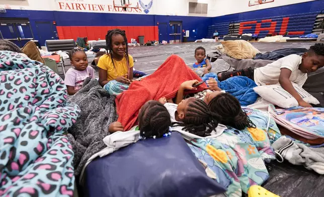 The grandchildren and great grandchildren of Vera Kelly, of Tallahassee, sit together after evacuating to a hurricane shelter at Fairview Middle School, ahead of Hurricane Helene, expected to make landfall here today, in Leon County, Fla., Thursday, Sept. 26, 2024. (AP Photo/Gerald Herbert)