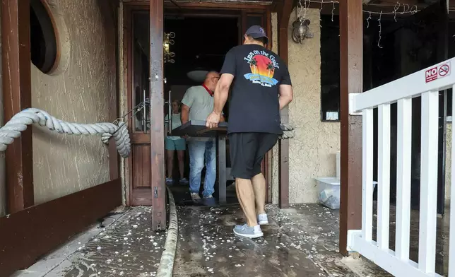 Staff of the Inn On The Gulf clean up after their restaurant flooded with surge from Hurricane Helene Friday, Sept. 27, 2024, in Hudson, Fla. (AP Photo/Mike Carlson)