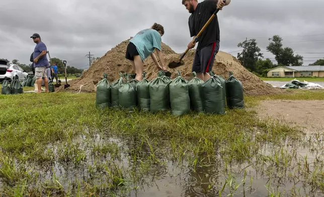 Rainwater accumulates around Nolan and Macie Melancon as they fill up sandbags for their home located a few miles away in Houma, La., as the region gets ready for the arrival of Hurricane Francine on Tuesday, Sept. 10, 2024. (Chris Granger /The Times-Picayune/The New Orleans Advocate via AP)