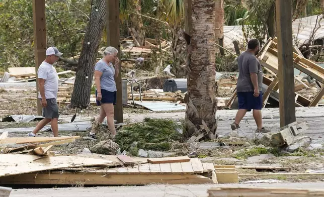 Jennifer Lange, center, walks amid the destruction in the aftermath of Hurricane Helene, in Horseshoe Beach, Fla., Saturday, Sept. 28, 2024. (AP Photo/Gerald Herbert)