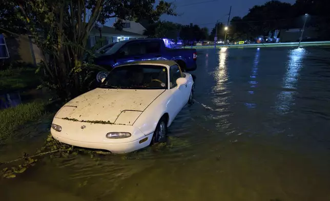 A car is submerged to its wheel well on Neyrey Dr. as water overflows the nearby W. Napoleon Ave drainage canal after a deluge of rain from Hurricane Francine in Metairie, La., in Jefferson Parish, Wednesday, Sept. 11, 2024. (AP Photo/Matthew Hinton)