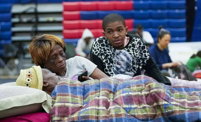 Bobby Joe Edwards, Sr., and his wife Lillie Edwards, of Walkalla, Fla., and their grandson Tavarrious Dixon, right, rest inside a hurricane evacuation shelter at Fairview Middle School, ahead of Hurricane Helene, expected to make landfall here today, in Leon County, Fla., Thursday, Sept. 26, 2024. (AP Photo/Gerald Herbert)