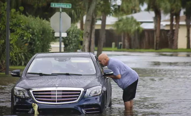 Melvin Juarbe, right, attempts to assist an unidentified driver whose car stalled in floodwaters from Hurricane Helene Thursday, Sept. 26, 2024 in Madeira Beach, Fla. The men tried to pull the car to dry land with their pickup truck but have opted to call AAA after several failed attempts. (Max Chesnes/Tampa Bay Times via AP)