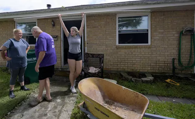 Kelsie Schmidt, right, walks a board to a debris pile from her family's home after floodwater came up a few inches in the house making most of the walls, floors, and doors wet after Hurricane Francine in Kenner, La., in Jefferson Parish, Thursday, Sept. 12, 2024. (AP Photo/Matthew Hinton)