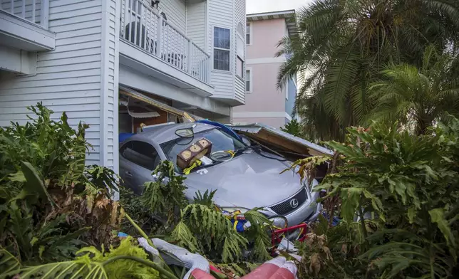 A vehicle sits outside of its garage after storm surge from Hurricane Helene, Saturday, Sept. 28, 2024, in Madeira Beach, Fla. (Luis Santana/Tampa Bay Times via AP)