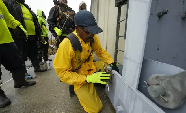 A workers from the Southeast Louisiana Flood Protection Authority-West locks a floodgates closed along the Harvey Canal, just outside the New Orleans city limits, in anticipation of Tropical Storm Francine, in Harvey, La., Tuesday, Sept. 10, 2024. (AP Photo/Gerald Herbert)