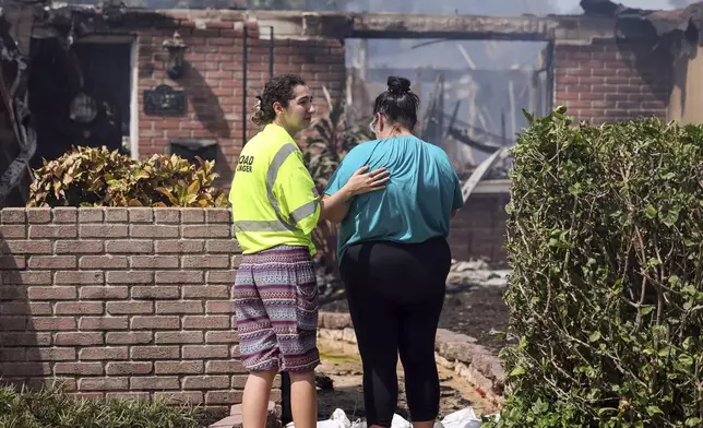 Faith Cotto comforts her mother Nancy as they look at the remains of their home which burned during the flooding from Hurricane Helene in the Shore Acres neighborhood Friday, Sept. 27, 2024, in St. Petersburg, Fla. (AP Photo/Mike Carlson)