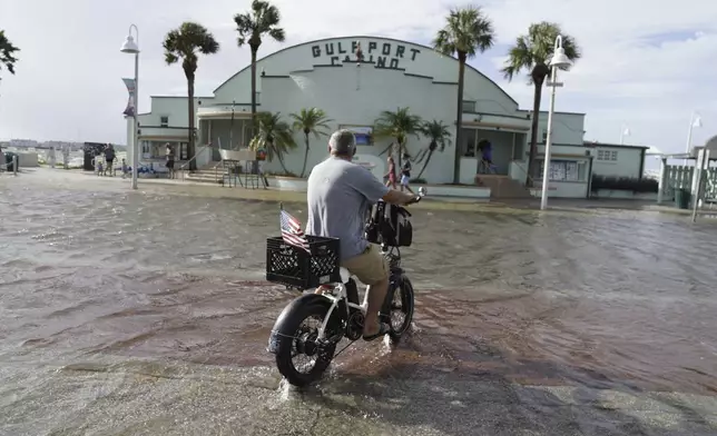 Louis Ward, 57, rides his bike along the the Gulfport waterfront as it takes on water as Hurricane Helene makes its way toward the Florida Panhandle, Thursday, Sept. 26, 2024 in Gulfport. (Martha Asencio-Rhine/Tampa Bay Times via AP)