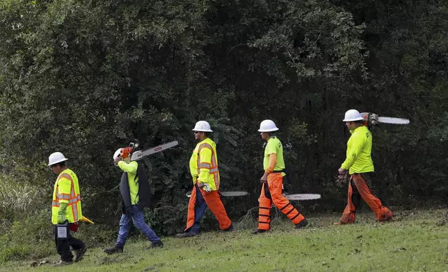 Crew members from Xylem Tree Experts walk to a staging area at Langley Pond Park in the aftermath of Hurricane Helene Sunday, Sept. 29, 2024, in Aiken, S.C. (AP Photo/Artie Walker Jr.)