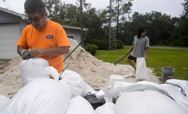 Jose Gonzales and his son Jadin Gonzales, 14, fill sand bags ahead of Hurricane Helene, expected to make landfall Thursday evening, Thursday, Sept. 26, 2024, in Clyattville, Ga. (AP Photo/Mike Stewart)