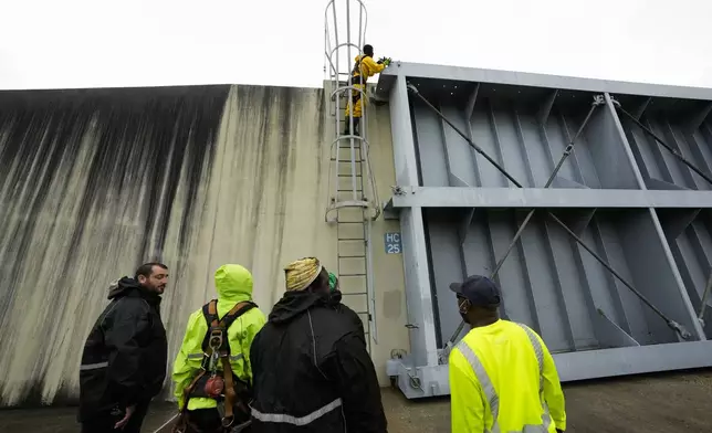 Workers from the Southeast Louisiana Flood Protection Authority-West close floodgates along the Harvey Canal, just outside the New Orleans city limits, in anticipation of Tropical Storm Francine, in Harvey, La., Tuesday, Sept. 10, 2024. (AP Photo/Gerald Herbert)