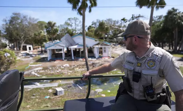 Capt. BJ Johnston, a law enforcement officer from the Florida Fish Wildlife and Conservation Commission surveys destruction from a high water buggy in the aftermath of Hurricane Helene, in Cedar Key, Fla., Friday, Sept. 27, 2024. (AP Photo/Gerald Herbert)