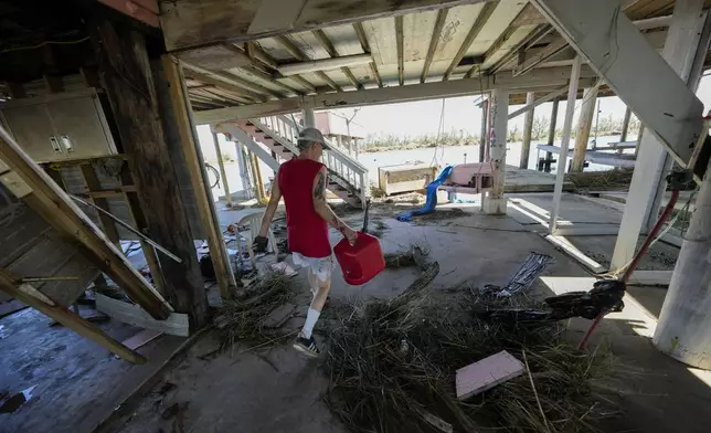 Resident Bill Andrews walks through debris under his home in the aftermath of Hurricane Francine in Cocodrie, La., Thursday, Sept. 12, 2024. (AP Photo/Gerald Herbert)