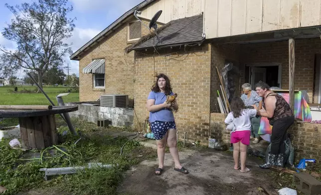 Bailee Boudreaux, 14, center, and her family bring out the chickens they let sleep in their house during the height of Hurricane Francine in Houma, La., Thursday, Sept. 12, 2024. (Chris Granger/The Times-Picayune/The New Orleans Advocate via AP)