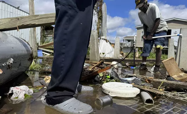 Brothers Wilson Garner, 73, left, and Carter Caldwell, 69, try to fix a broken water pipe, Thursday, Sept. 12, 2024, in Ashland, La., in the aftermath of Hurricane Francine. (AP Photo/Jack Brook)