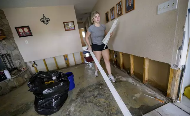 Kelsie Schmidt, right, walks a board to a debris pile from her family's home after floodwater came up a few inches in the house making most of the walls, floors, and doors wet after Hurricane Francine in Kenner, La., in Jefferson Parish, Thursday, Sept. 12, 2024. (AP Photo/Matthew Hinton)