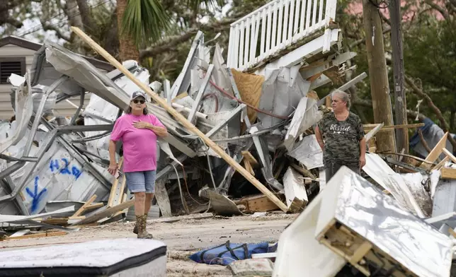 Frankie Johnson, left, talks with fellow resident Charlene Huggins, whose home was destroyed, amid the destruction in the aftermath of Hurricane Helene, in Horseshoe Beach, Fla., Saturday, Sept. 28, 2024. (AP Photo/Gerald Herbert)