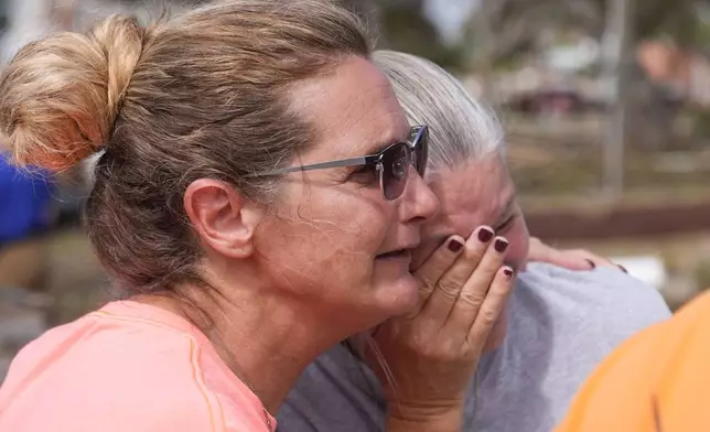 Tammy Bryan, left, hugs fellow resident Jennifer Lange amid the destruction in the aftermath of Hurricane Helene, in Horseshoe Beach, Fla., Saturday, Sept. 28, 2024. (AP Photo/Gerald Herbert)