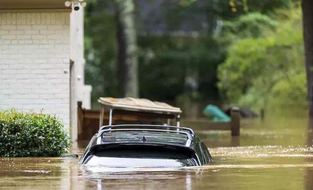 A vehicle is submerged outside a home near Peachtree Creek in Atlanta Friday, Sept. 27, 2024. (AP Photo/Jason Allen)