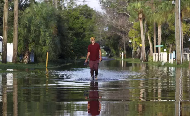 James Wilder, 55, of New Port Richey, Fla., walks along a flooded street from Hurricane Helene at Green Key Road near US 19 Friday, Sept. 27, 2024 in New Port Richey. (Chris Urso/Tampa Bay Times via AP)