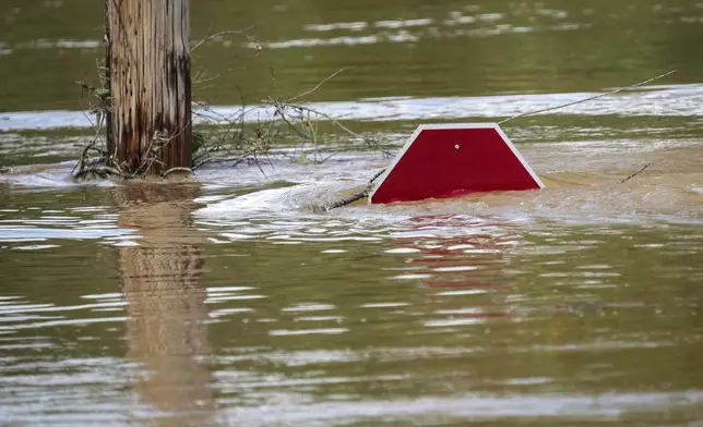 A stop sign can be barely seen above a flooded parking lot after torrential rain from Hurricane Helene caused severe flooding, Saturday, Sept. 28, 2024, in Morganton, N.C. (AP Photo/Kathy Kmonicek)