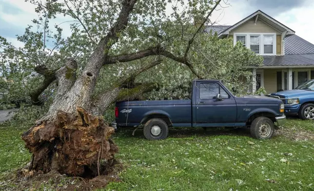 An uprooted tree landed on a pickup truck in front of a home on East Main Street after Hurricane Helene, Saturday, Sept. 28, 2024, in Glen Alpine, N.C. (AP Photo/Kathy Kmonicek)