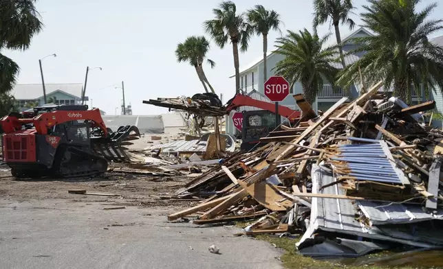 Workers remove debris in the aftermath of Hurricane Helene, in Cedar Key, Fla., Friday, Sept. 27, 2024. (AP Photo/Gerald Herbert)
