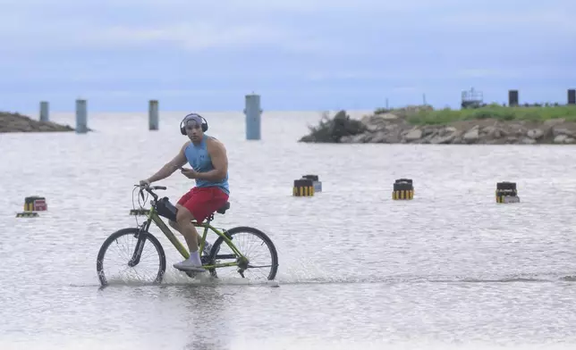 Geral (cq) Hammond pedals through flood water from Hurricane Francine near the entrance to the Treasure Chest Casino in Kenner, La., in Jefferson Parish, Thursday, Sept. 12, 2024. (AP Photo/Matthew Hinton)