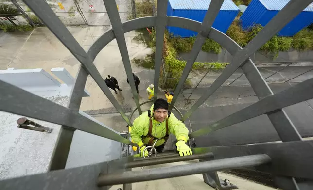 Delwyn Bodden, a worker for the Southeast Louisiana Flood Protection Authority-West climbs a ladder up a floodgate to lock it closed along the Harvey Canal, just outside the New Orleans city limits, in anticipation of Tropical Storm Francine, in Harvey, La., Tuesday, Sept. 10, 2024. (AP Photo/Gerald Herbert)