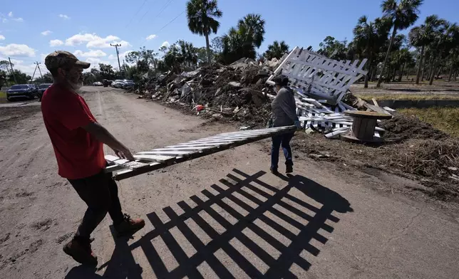 Workers pile debris in the aftermath of Hurricane Helene, in Jena, Fla., Sunday, Sept. 29, 2024. (AP Photo/Gerald Herbert)