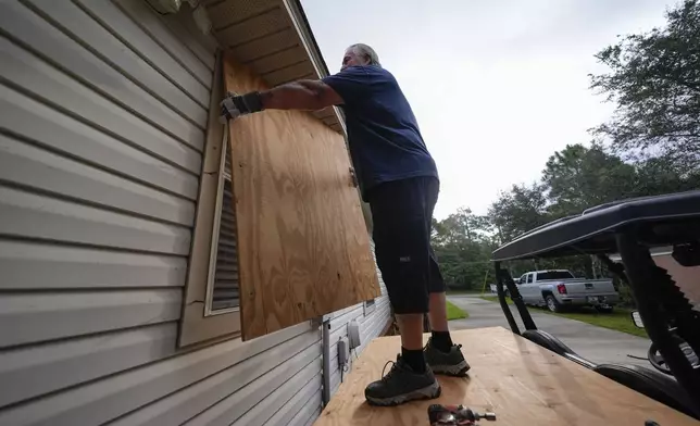 Dave McCurley boards up the windows to his home in advance of Tropical Storm Helene, expected to make landfall as a hurricane, in Ochlockonee Bay, Fla., Wednesday, Sept. 25, 2024. (AP Photo/Gerald Herbert)