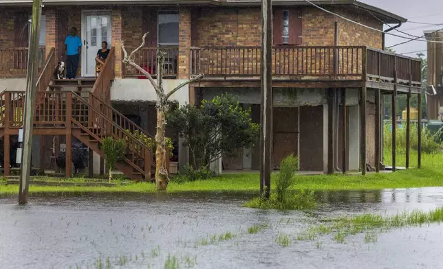 Dulac residents, top left, sit on their front porch as they watch water rise around their elevated home as the effects of Hurricane Francine are felt along the Louisiana coast on Wednesday, Sept. 11, 2024. (Chris Granger/The Times-Picayune/The New Orleans Advocate via AP)