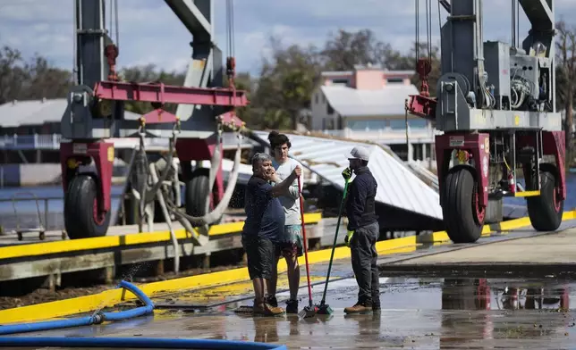 Workers clean up a dock where a boat shed was destroyed in the aftermath of Hurricane Helene, in Jena, Fla., Sunday, Sept. 29, 2024. (AP Photo/Gerald Herbert)