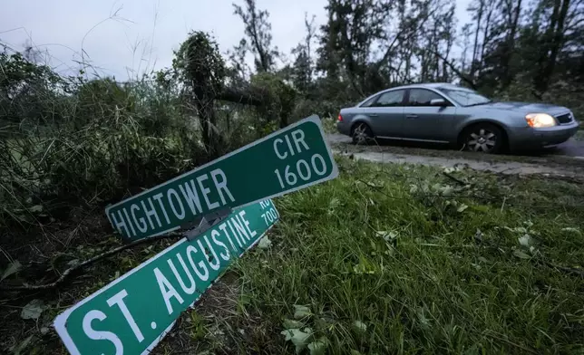 Vehicles move slowly around trees that have fallen after of Hurricane Helene moved through the area, Friday, Sept. 27, 2024, in Valdosta, Ga. (AP Photo/Mike Stewart)