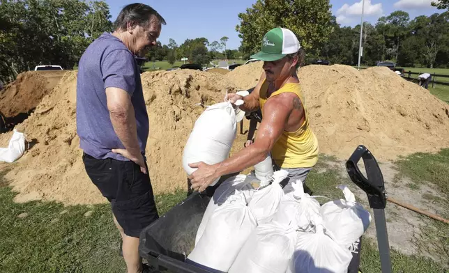 Residents Dennis Lusby, left, and John Guerra fill sandbags at the Orange County distribution site at Barnett Park in Orlando, Fla., Tuesday, Sept. 24, 2024, ahead of the forecast for the possibility of heavy rains in Central Florida. (Joe Burbank/Orlando Sentinel via AP)