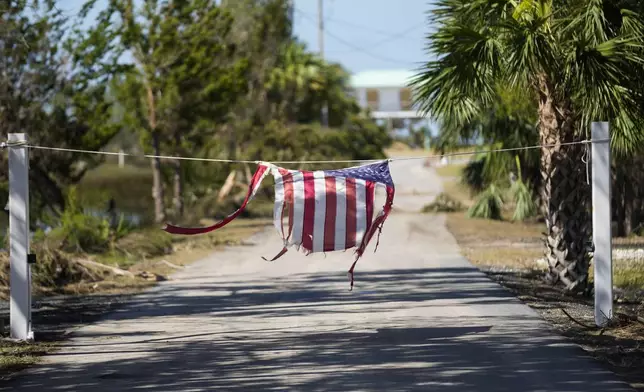 A tattered American flag hangs on a rope on a now closed road in the aftermath of Hurricane Helene, in Jena, Fla., Sunday, Sept. 29, 2024. (AP Photo/Gerald Herbert)