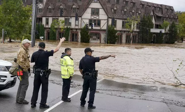 Emergency personnel watch as floodwaters rise, Friday, Sept. 27, 2024, in Asheville, N.C. (AP Photo/Erik Verduzco)