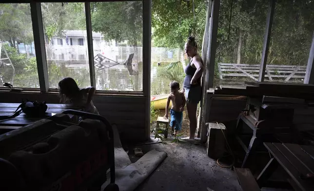 Hailey Morgan, right, surveys the damage to their flooded home after returning with her children, Aria Skye Hall, 7, left, and Kyle Ross, 7, in the aftermath of Hurricane Helene, Friday, Sept. 27, 2024, in Crystal River, Fla. Morgan stayed with her grandmother and her children in Hernando, Fla., as the storm made landfall. (AP Photo/Phelan M. Ebenhack)