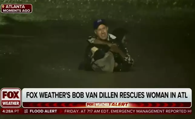 In this image made from a Fox Weather broadcast, meteorologist Bob Van Dillen rescues a woman stuck in floodwaters caused by Hurricane Helene in Atlanta, Friday, Sept. 27, 2024. (Fox Weather via AP)