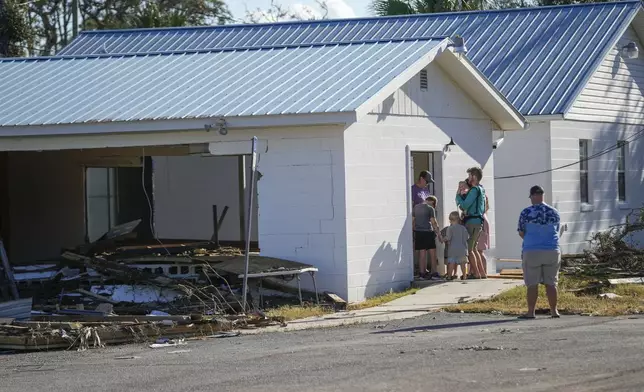 A group from St. Augustine, Fla. that arrived to help storm victims, who did not want to give their name, pray outside the damaged First Baptist Church in the aftermath of Hurricane Helene, in Horseshoe Beach, Fla., Sunday, Sept. 29, 2024. (AP Photo/Gerald Herbert)