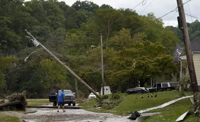 A person crosses River St. where flood damage is seen Saturday, Sept. 28, 2024, in Newport, Tenn. (AP Photo/George Walker IV)