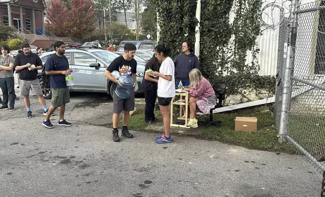 People wait to gather water at Mountain Valley Water in the aftermath of Hurricane Helene in West Asheville, N.C., Monday, Sept. 30, 2024 (AP Photo/Jeffrey Collins)