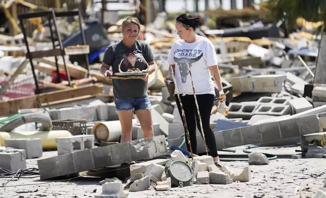 Gloriana Cherry, left, recovers possessions from her family's destroyed home, along with Shannon Lee, in the aftermath of Hurricane Helene, in Horseshoe Beach, Fla., Saturday, Sept. 28, 2024. (AP Photo/Gerald Herbert)