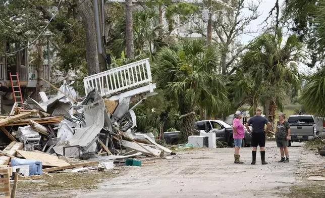 Frankie Johnson, left, and her husband, Mark Johnson, talk with fellow resident Charlene Huggins, right, amid the destruction in the aftermath of Hurricane Helene, in Horseshoe Beach, Fla., Saturday, Sept. 28, 2024. (AP Photo/Gerald Herbert)