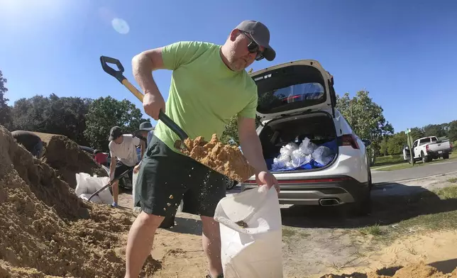 Justin Fogle, of College Parks, fills a sandbag at the Orange County distribution site at Barnett Park in Orlando, Fla., Tuesday, Sept. 24, 2024, ahead of the forecast for the possibility of heavy rains in Central Florida. (Joe Burbank/Orlando Sentinel via AP)