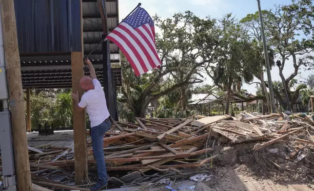 John Taylor puts up an American flag on his destroyed property in the aftermath of Hurricane Helene, in Horseshoe Beach, Fla., Saturday, Sept. 28, 2024. (AP Photo/Gerald Herbert)